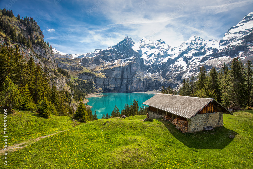Obraz premium Amazing tourquise Oeschinnensee with waterfalls, wooden chalet and Swiss Alps, Berner Oberland, Switzerland.