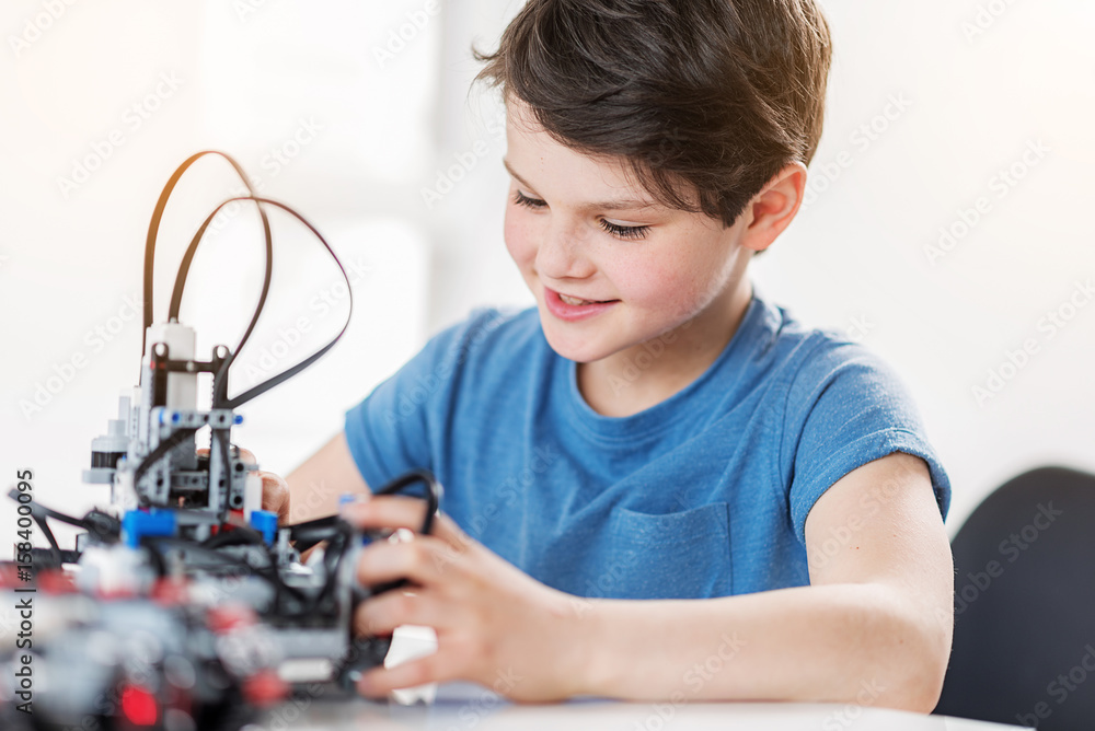 Interested smiling male child checking robot Interested smiling male child checking robot