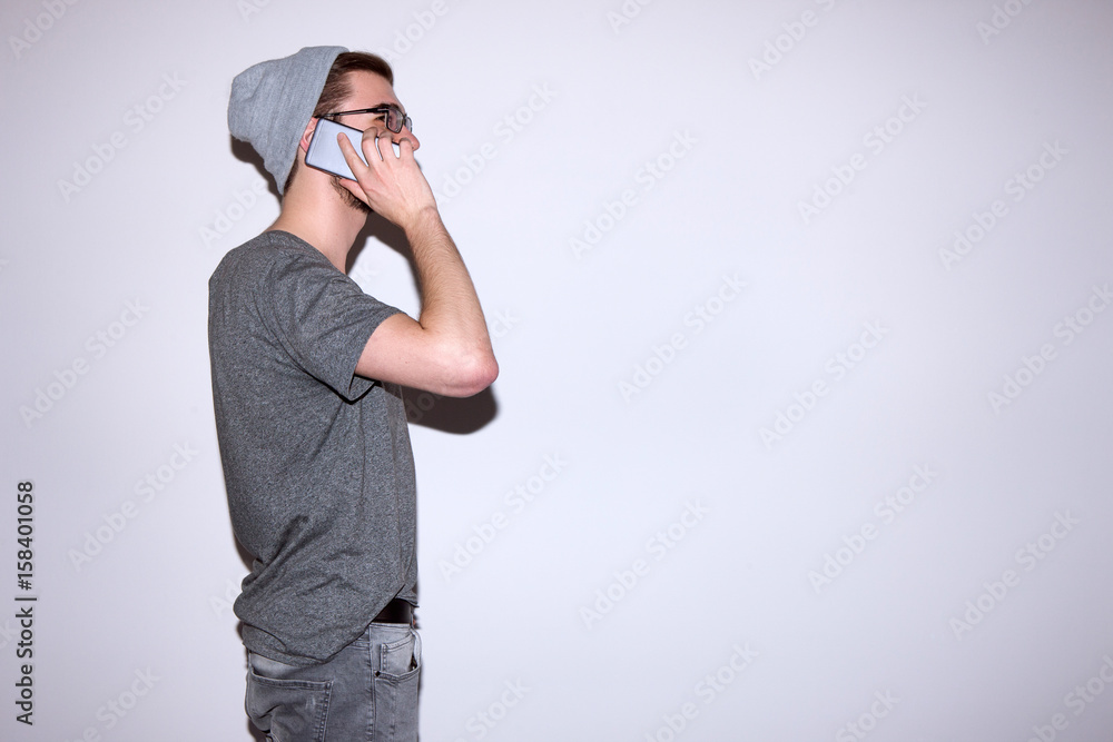 Man in gray speak at smartphone. Modern style. Business, communication, friendship, social network concept. Fashionable guy stay on white background Man in gray speak at smartphone. Modern style. Business, communication, friendship, social network concept. Fashionable guy stay on white background