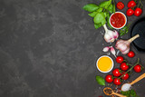 Cooking background. Ingredients and spices for cooking dinner: tomatoes, greens, salt, pepper, garlic. With a frying pan, on a black concrete table. Top view