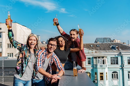 Cheerful young people hanging out on rooftop terrace