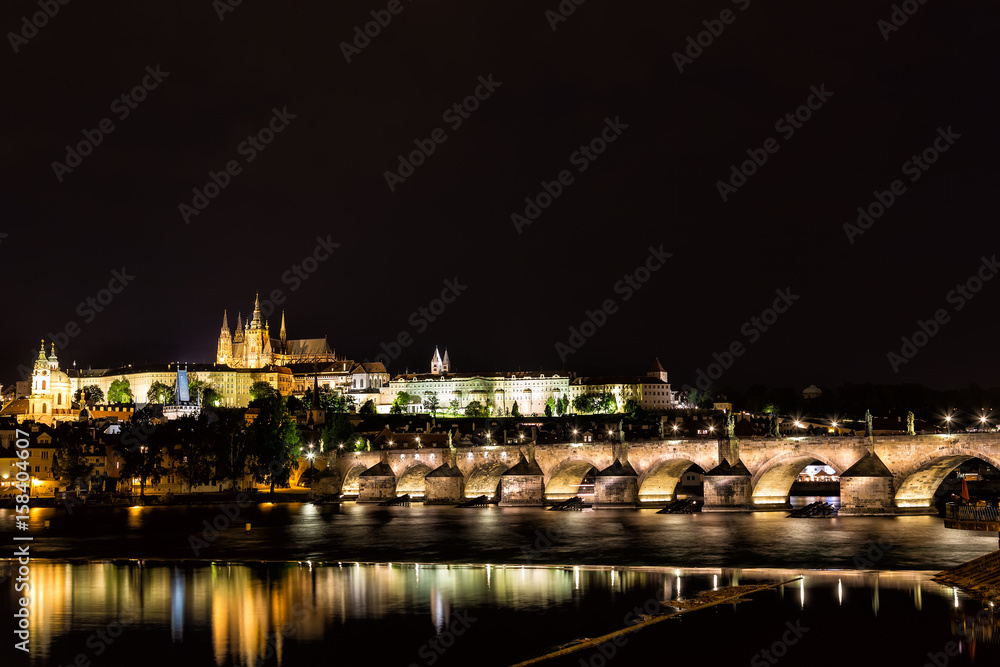 The Prague Castle and the Charles Bridge over Vltava river with nice water reflections at night in Prague, Czech Republic