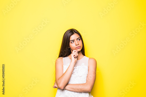 portrait of the beautiful young woman thinking, dreaming on the yellow background