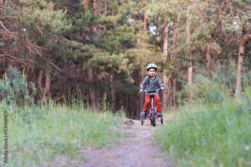 Child riding a bicycle. Kid in a helmet riding a bike in the forest. Beautiful baby. Authentic color.