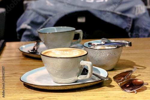Fotografía Cup of cappuccino with a pattern and a sugar bowl with brown and white sugar are