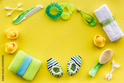 baby accessories for bath with body cosmetic and ducks on yellow background top view mock-up