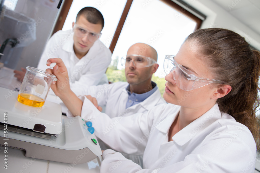 Female scientists weighing glass beaker Female scientists weighing glass beaker