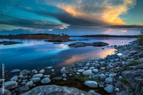 There are many stones near the shore. Reflection of the sky in the water. Northern landscape. Wild nature of the north. Karelia. Ladoga lake.
