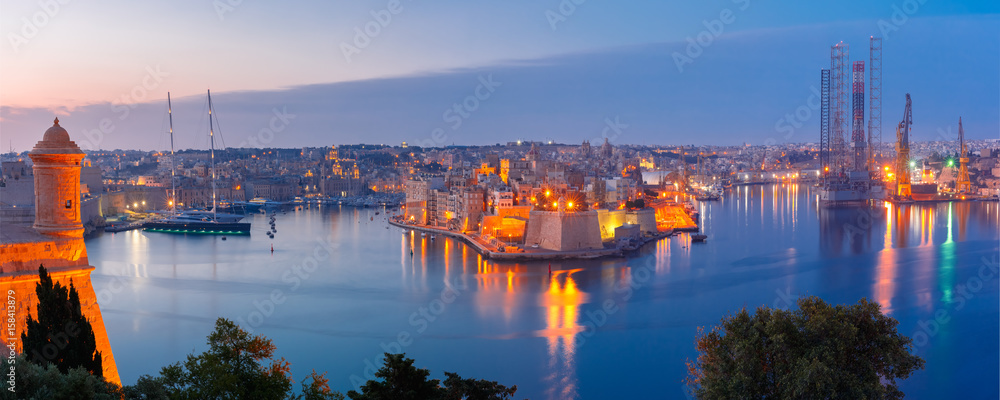 Panoramic aerial skyline view of ancient defences of Three cities, three fortified cities of Birgu, Senglea and Cospicua and Grand Harbor with ships, as seen from Valletta during morning blue hour