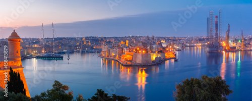 Panoramic aerial skyline view of ancient defences of Three cities, three fortified cities of Birgu, Senglea and Cospicua and Grand Harbor with ships, as seen from Valletta during morning blue hour photo