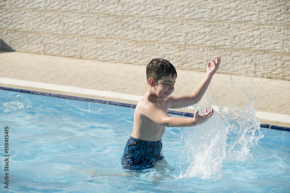 Caucasian boy having fun inside swimming pool during summer time