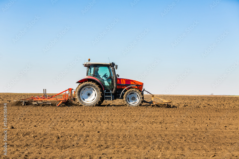 Farmer in tractor preparing land with seedbed cultivator as part of pre seeding activities in early spring season of agricultural works at farmlands. Farmer in tractor preparing land with seedbed cultivator as part of pre seeding activities in early spring season of agricultural works at farmlands.