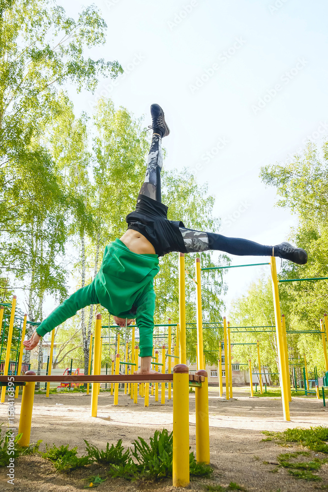 Fototapeta premium Fitness man at the bar. Exercising outdoors in the Park. Street workout.