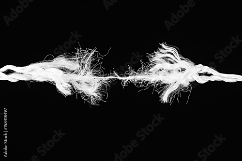 Tearing white the rope in the middle of the frame obn the black background
