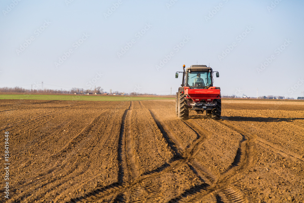 Fototapeta premium Farmer fertilizing arable land with nitrogen, phosphorus, potassium fertilizer