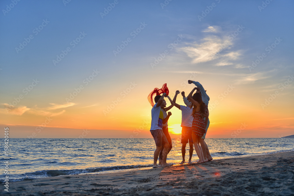 group of happy young people dancing at the beach on beautiful summer ...