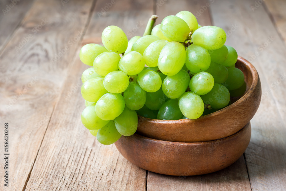 Bunch of green ripe grapes in wooden bowl, copy space Bunch of green ripe grapes in wooden bowl, copy space