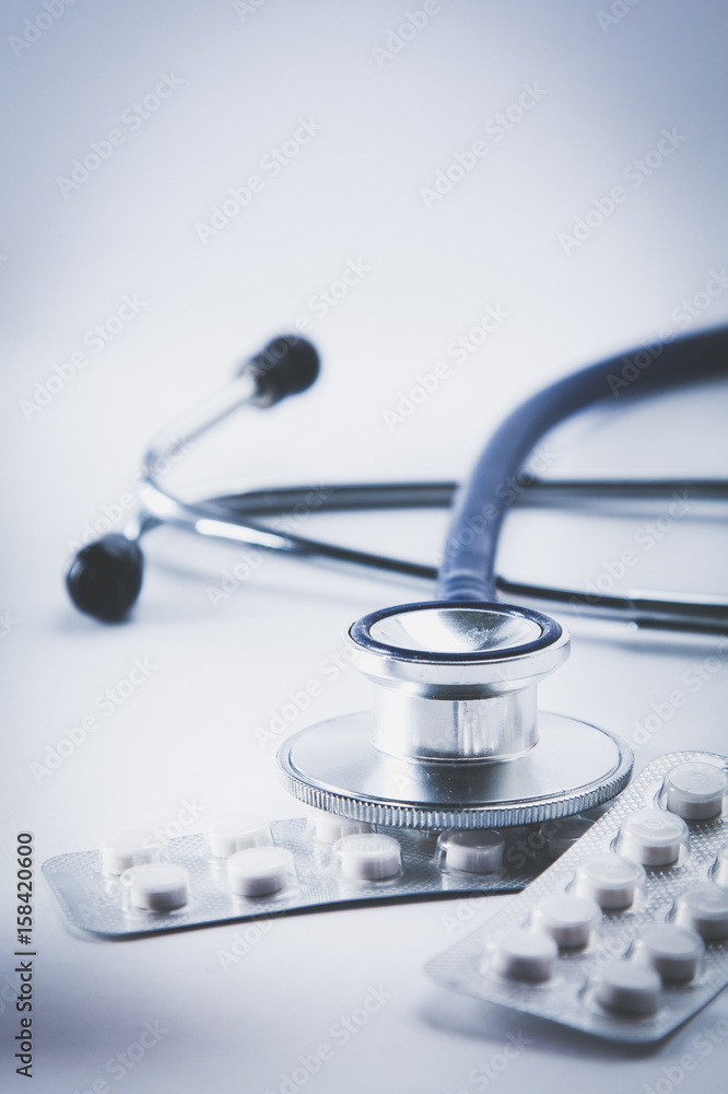 Bottles of pills and a medical stethoscope on white background Bottles of pills and a medical stethoscope on white background