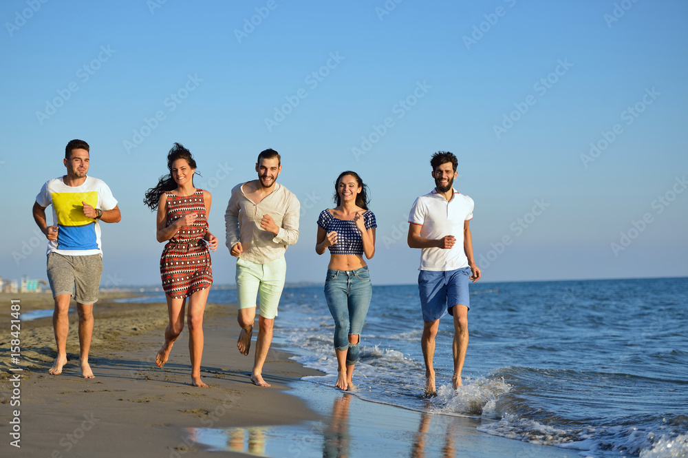 Group of friends having fun walking down the beach at sunset