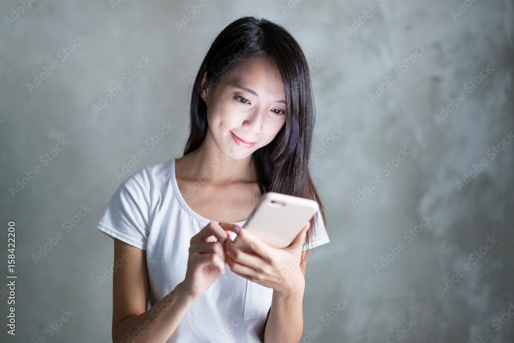 Woman use of mobile phone over grey background Woman use of mobile phone over grey background