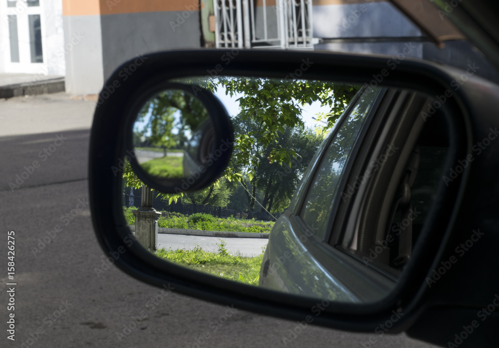 the reflection of nature in the mirror of the car in the yard