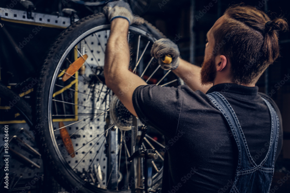 Mechanic repairing bicycle wheel tire in a workshop.