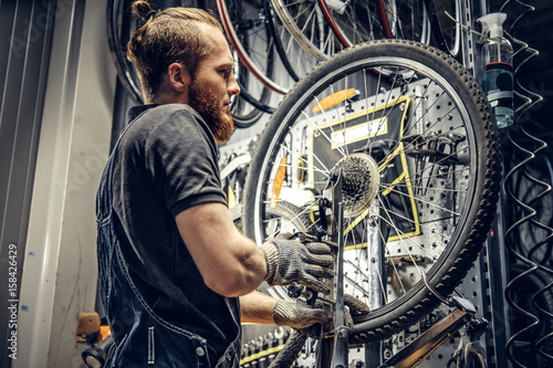 Mechanic removing bicycle rear cassette in a workshop.