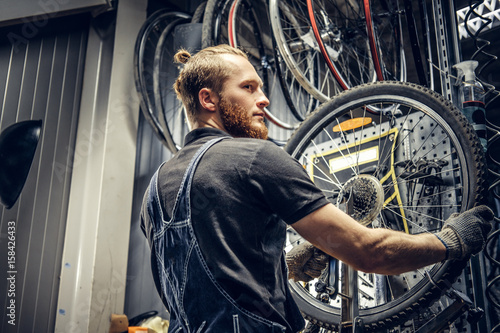 Mechanic repairing bicycle wheel tire in a workshop. © Fxquadro