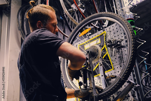 Mechanic removing bicycle rear cassette in a workshop.