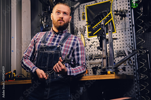 Bicycle mechanic in a workshop with bike parts on background.