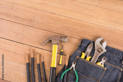 Several tools in a denim workers pocket  on wood planks