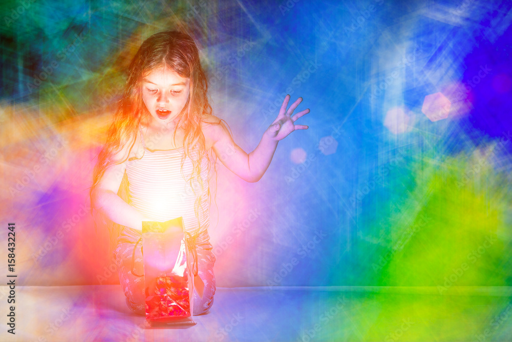 Girl looks in a red glowing gift bag on a colorful background Girl looks in a red glowing gift bag on a colorful background