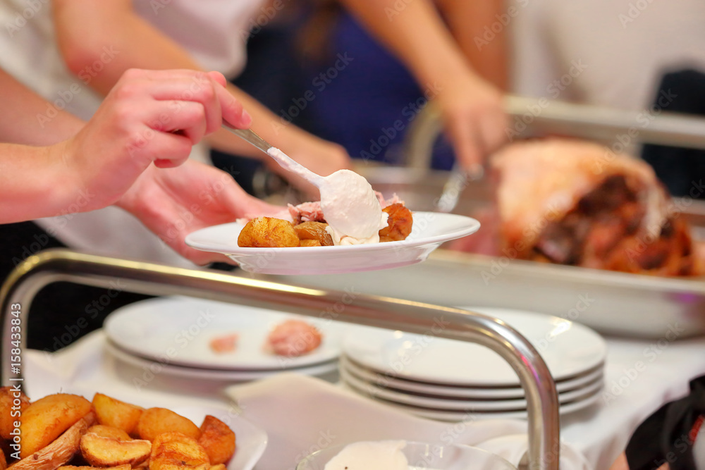 waiter serves roasted meat and baked potatoes at the party waiter serves roasted meat and baked potatoes at the party