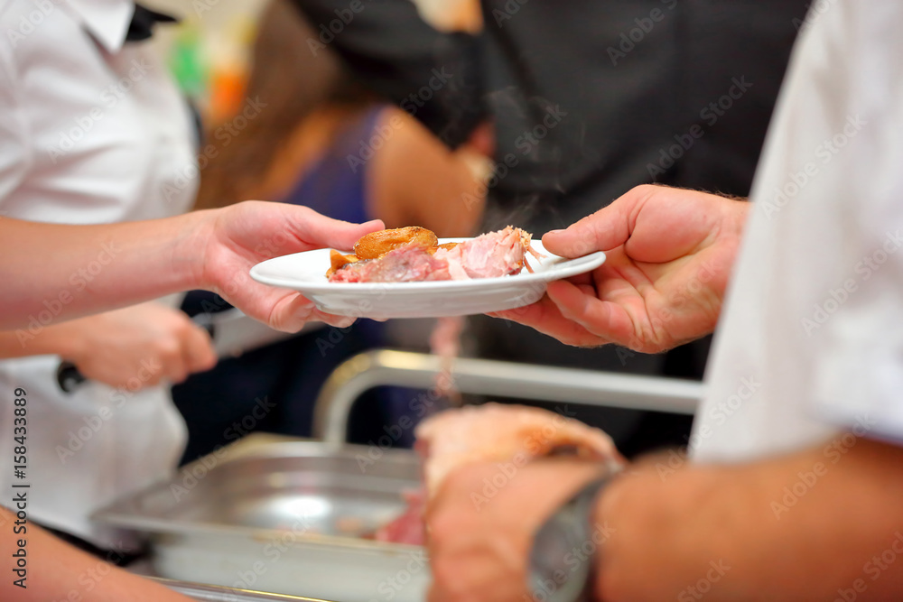 waiter serves roasted meat and baked potatoes at the party