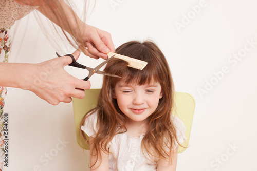 Fotografie Mother cuts daughter's hair at home