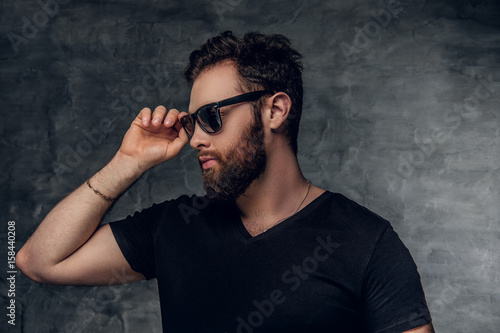 Stylish bearded male in sunglasses over grey background.