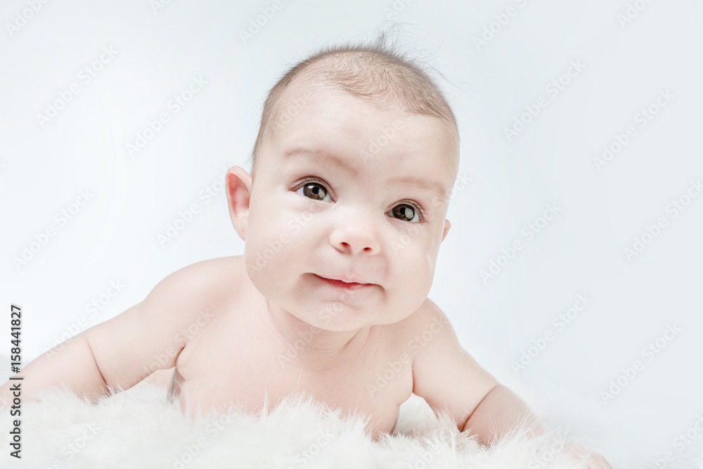 Smiling baby lies on a white fluffy background Smiling baby lies on a white fluffy background