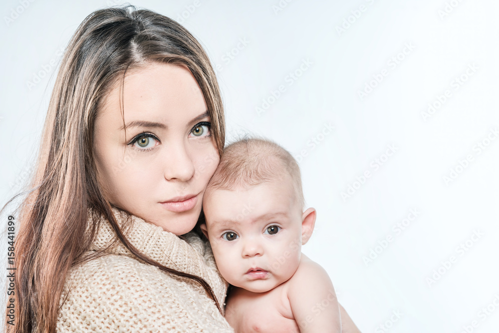 Woman in a sweater is holding a baby on a white background Woman in a sweater is holding a baby on a white background
