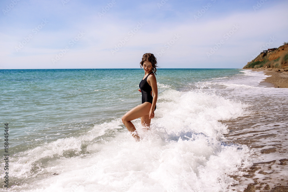 High fashion look.glamor beautiful sexy stylish brunette young female model with bright make-up, with perfect sunbathing clean skin in a black swimsuit on the beach in fashion style High fashion look.glamor beautiful sexy stylish brunette young female model with bright make-up, with perfect sunbathing clean skin in a black swimsuit on the beach in fashion style