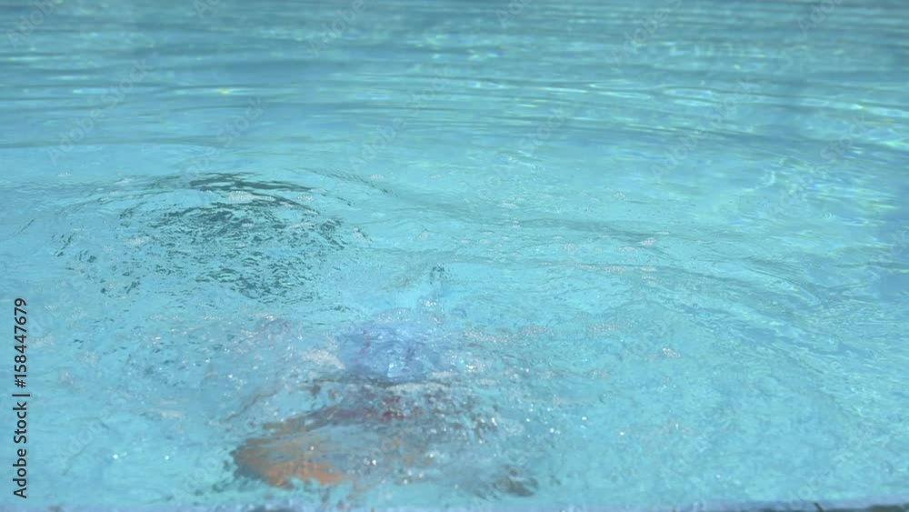 Slow motion of little girl diving into water in swimming pool. Concept of sport and leisure.