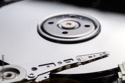 Opened hard disk with close-up spindel, platter, acuator arm.  photo