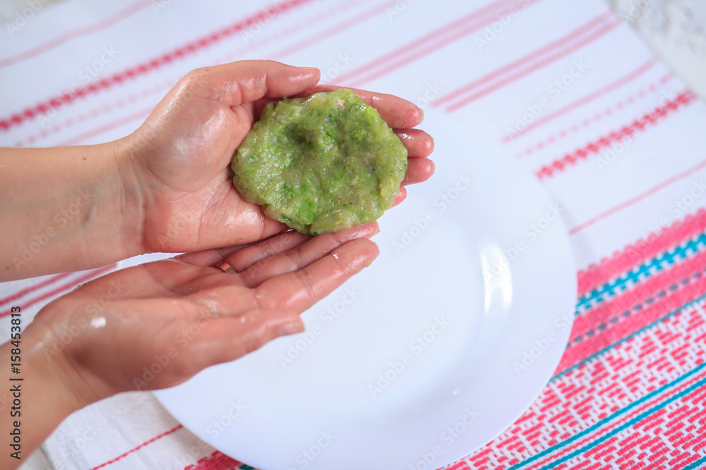 Crude forcemeat cutlet with a stuffing in a hand on a light background