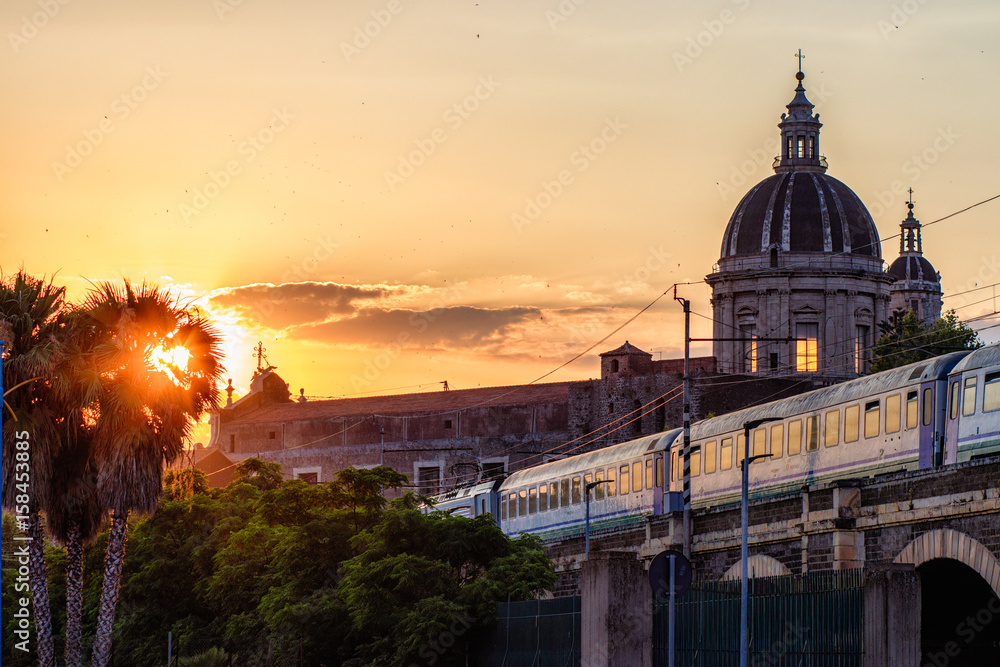 Catania, passing the train at sunset over the marina arches (archi della marina). View of the ancient walls.