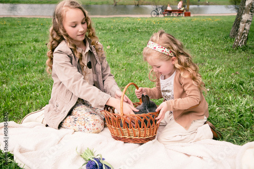 two girls playing with rabbit in the park
