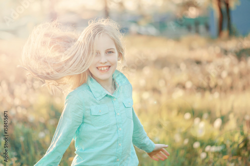 Beautiful smiling teenage girl in blouse  against green of summer park. Sunlight  happiness  fun  hair  joy.