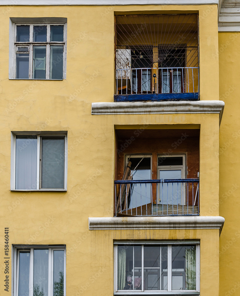 Three big balconies on yellow wall with windows