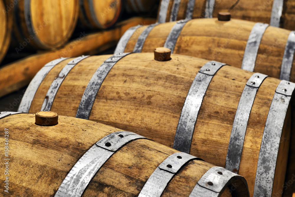 Wine barrels and metal cisterns in dark cellar Wine barrels and metal cisterns in dark cellar