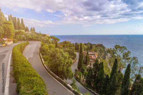 Fototapeta Naklejka Na Ścianę i Meble -  Taormina, Sicily - The streets of the famous hilltop town of Taormina with palm tree, mediterranean sea and sunshine