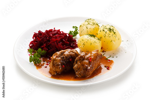 Wrapped pork chops with potatoes and beetroots on white background