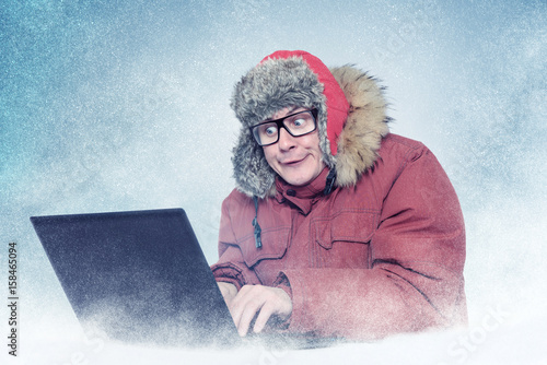 Funny man in winter clothes with laptop, cold, snow. 
 photo